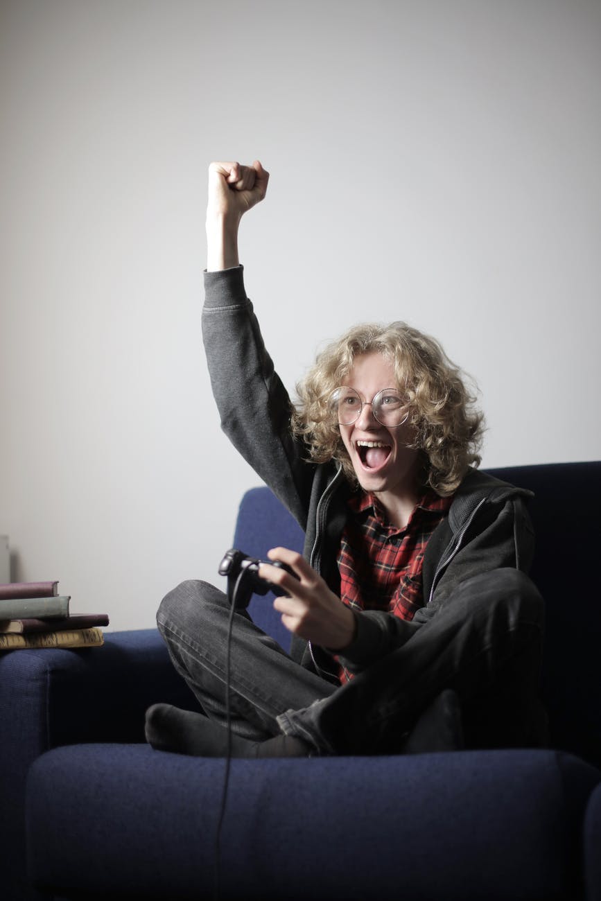cheerful male teen playing video game on couch